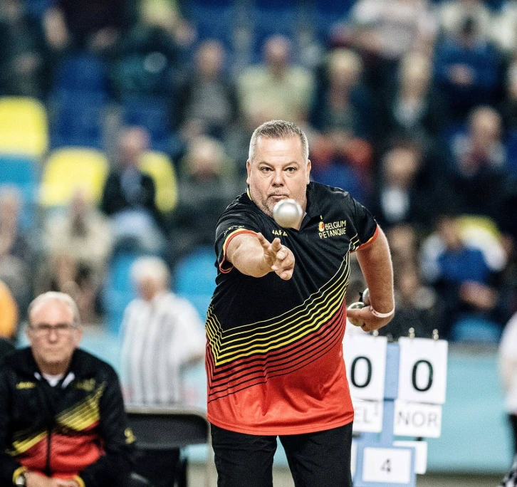 Belgische speler in zwart-rood-geel shirt gooit een boule
